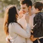 Family sharing affectionate moments outdoors with parents and child enjoying the sunny day.