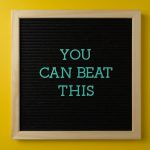Black letter board with motivational phrase 'You Can Beat This' on vibrant yellow background.